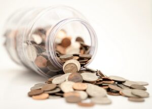 Coins spilling out of glass jar to save money being responsible